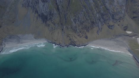 Aerial-view-away-from-the-Kvalvika-and-Vestervika-beaches,-in-cloudy-Lofoten,-Norway---tilt,-drone-shot