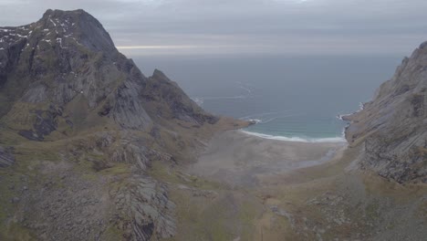 Aerial-view-overlooking-a-beach,-between-mountains-in-Lofoten,-Norway---circling,-drone-shot