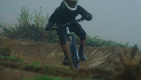 Ein-Downhill-Mountainbiker-Dreht-Im-Nebel-Eine-Kurve