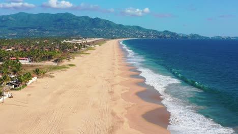 Aerial-towards-Pie-de-la-Cuesta,-beachfront-waves-crashing-on-sand-shore,-Mexico