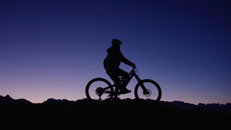 A-cyclist-is-standing-on-top-of-a-ridge-at-dawn