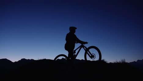 A-mountain-biker-is-posing-at-the-top-of-a-mountain-at-sunrise
