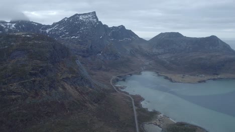 Aerial-drone-view-overlooking-a-shoreline-road-cloudy-fall-day-in-Lofoten,-Norway
