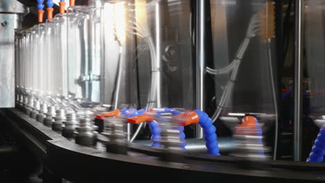 A-line-of-bottles-made-by-industrial-blowing-from-PET-preform-is-sliding-on-a-piece-of-robotic-equipment