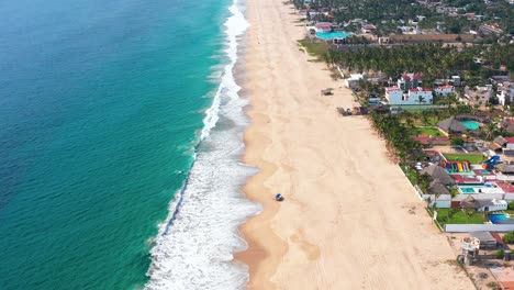 Aerial-pullback-Pie-de-la-Cuesta-Sandy-beach-shore,-emerald-water,-Acapulco-Guerrero