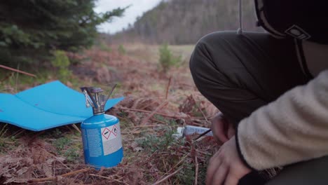 Man-With-Portable-Camping-Burner-Is-Setting-To-Boil-Water-Near-Forest-Mountains
