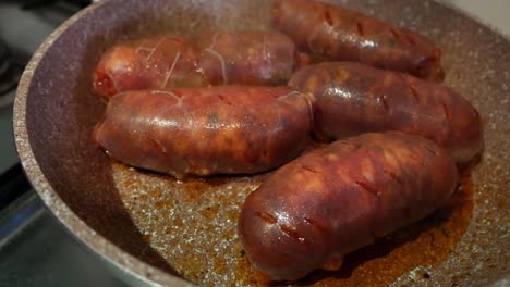 Very-close-up-of-some-big-and-bright-red-chorizo-sausages-being-cooked-on-a-pan