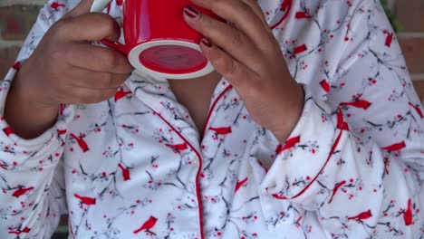 Medium-Shot-of-Black-woman-drinking-warm-coffee-while-wearing-warm-pajamas