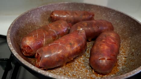 Close-up-of-some-big-and-bright-red-chorizo-sausages-being-cooked-on-a-pan