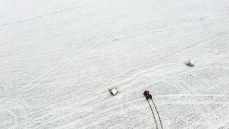 Ansicht-Von-Oben-Nach-Unten-Eines-Mannes,-Der-Auf-Einem-Mit-Schnee-Gefüllten-Gras-Ein-ATV-Fährt