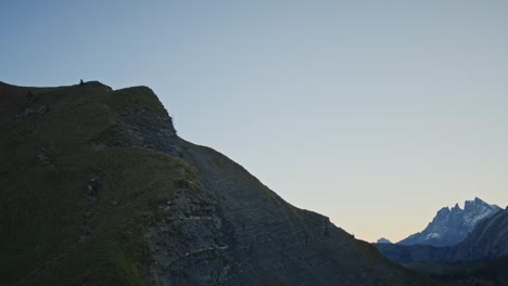 A-mountain-biking-is-carrying-his-bike-up-a-steep-and-exposed-alpine-ridge-at-dawn