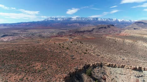 Drone-shot-of-a-large-plateau-in-the-desert-with-mountains-in-the-distance