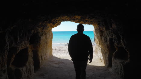 Un-Hombre-Mirando-Por-Un-Túnel-Hacia-La-Playa-Y-El-Océano-Durante-El-Día