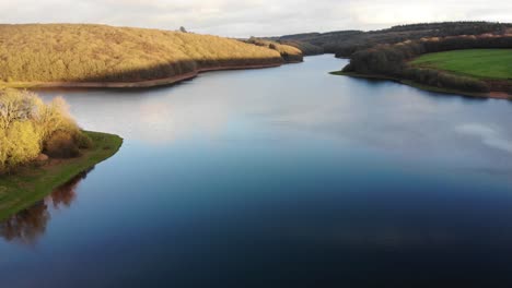 Aerial-backwards-shot-of-Wimbleball-Lake-Exmoor-highlighting-the-amazing-calm-water-of-the-lake-and-reflection-of-the-sky