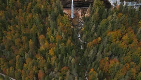 Establishing-shot-of-Pericnik-waterfall-in-autumn-colored-pine-forest,-aerial