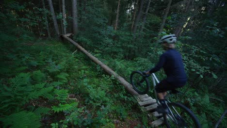Ein-Mountainbiker-Fährt-An-Einem-Schmalen-Umgestürzten-Baum-Entlang