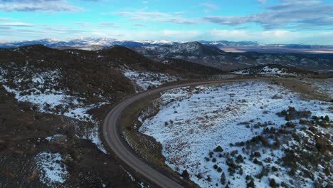 Drone-aerial-view-of-a-large-bending-highway-amongst-mountains-and-snow