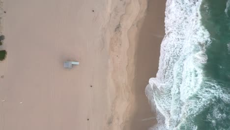 Lifeguard-Tower-At-The-Empty-Beach-With-Foamy-Waves-In-The-Shoreline