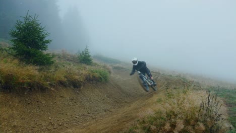 A-mountain-biker-rides-an-alpine-trail-covered-in-fog