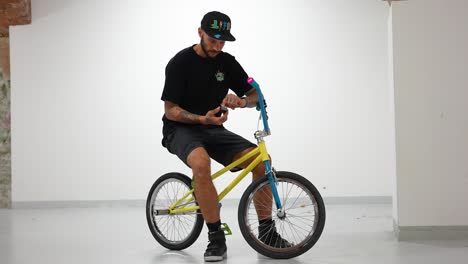 BMX-rider-sitting-on-his-bike,-setting-up-his-action-camera