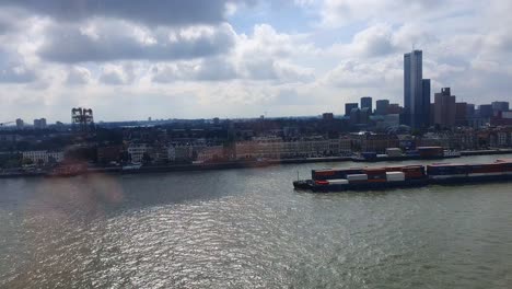 Blick-Durch-Das-Fenster-Des-Containerkahns,-Der-Auf-Der-Nieuwe-Maas-Vorbeifährt,-Mit-Der-Skyline-Von-Rotterdam-Im-Hintergrund