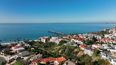 Slow-motion-aerial-view-of-San-Clemente-coastline-and-beach-during-blue-sky-day