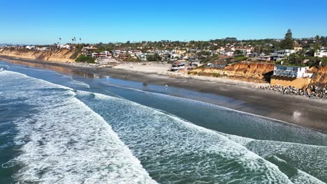 Aerial-backward-moving-shot-of-residential-houses-and-hotels-along-the-beaches-of-Encinitas,-California,-USA-on-a-bright-sunny-day