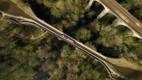 Canal-Boat-Barge-Travelling-Along-Canal-From-Above-In-English-Countryside-Rotating-Aerial-Shot