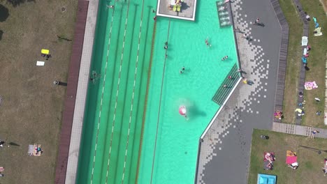 Top-Luftaufnahme-Des-Swimmingpools-Mit-Menschen,-Die-Sich-Im-Wasser-Amüsieren-Und-Decken-Auflegen-4k