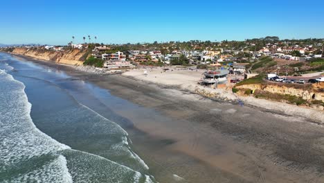 Aerial-shot-moving-from-right-to-left-of-residential-houses-and-hotels-along-Moonlight-Beach-in-Encinitas,-California,-the-USA-with-waves-crashing-on-the-beach