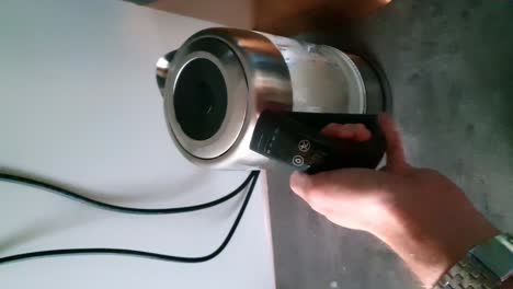 Hand-Trying-To-Turn-On-Glass-Electric-Kettle-With-Water