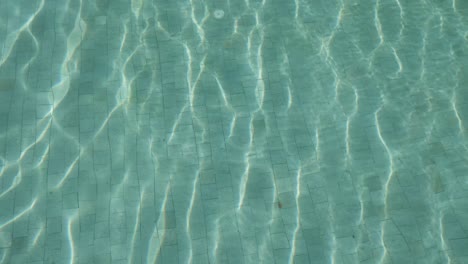 Blick-Auf-Die-Wasseroberfläche-Im-Schwimmbad-Mit-Sonnenlicht,-Das-Auf-Der-Oberfläche-Reflektiert-Wird