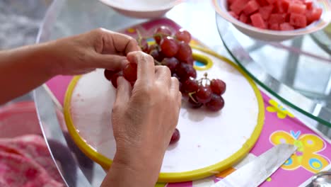 Female-hands-pick-grape-berries-from-cluster-preparing-fruit-dessert,-close-up