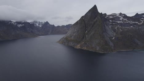 Aerial-view-overlooking-the-Reinefjord,-in-cloudy,-Lofoten,-Norway---pan,-drone-shot