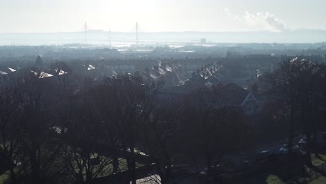 Frosty-mist-surrounding-urban-British-town-house-rooftops-aerial-view-early-morning-descending-to-park-trees