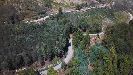 Pequeña-Caravana-Blanca-Que-Sube-Por-Un-Camino-Al-Lado-De-Las-Montañas-En-Portugal,-Filmada-En-Un-Dron