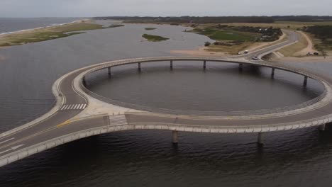 Isolated-car-driving-on-circular-bridge-at-Laguna-Garzon,-Uruguay
