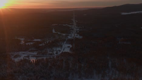 Sunset-on-Snow-covered-Road-And-Forest-in-Southern-Quebec,-Canada---aerial-drone-shot