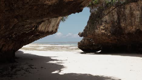 Bajo-La-Sombra-De-Formaciones-Rocosas-En-La-Playa-De-Arena-Blanca,-Mtende,-Zanzíbar,-Tanzania