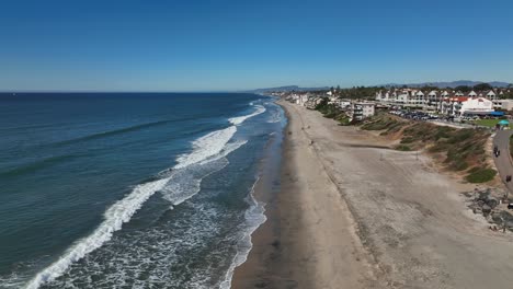 Aerial-drone-shot-running-parallel-along-the-coastline-of-Carlsbad,-California,-USA-on-a-bright-sunny-day
