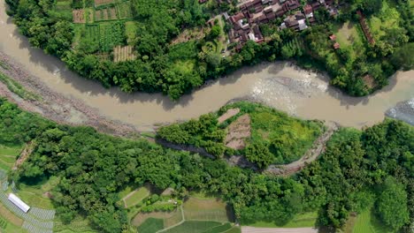 Overhead-aerial-push-in-of-dirty-Progo-River-in-sunlight-in-Indonesia