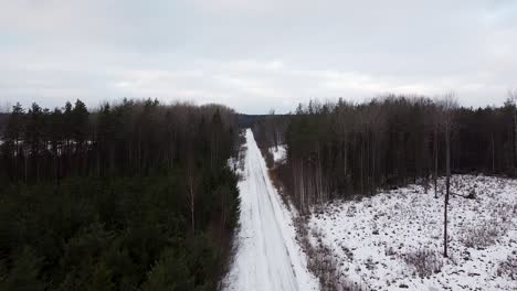 Aerial-drone-rising-up-a-small-winter-road-in-South-Estonia