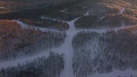 Campos-Cubiertos-De-Nieve-Con-árboles-Densos-En-El-Sur-De-Quebec-Canadá-Durante-La-Puesta-De-Sol---Retroceso-Aéreo