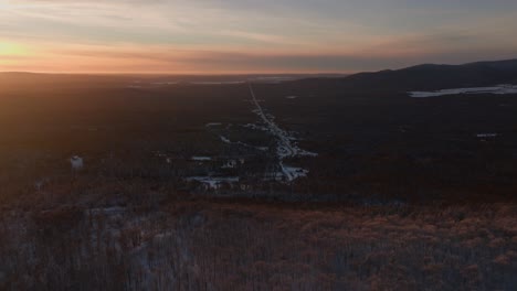Luftaufnahme-Des-Schneebedeckten-Bergwaldes-Und-Der-Straße-Auf-Dem-Land-Im-Südlichen-Quebec,-Kanada-Bei-Sonnenuntergang-Im-Winter