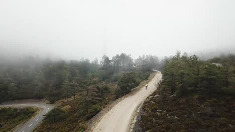 Group-of-cyclists-going-up-a-dirt-road-with-intense-fog
