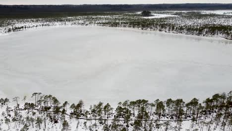 Aerial-drone-rotating-above-Luhasoo-bog-lake-in-winter