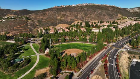Aerial-shot-of-a-baseball-field-and-hill-on-the-background-in-San-Elijo-Hills-over-San-Marcos,-California,-USA-on-a-bright-sunny-morning