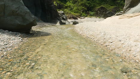 Top-down-closeup-view-of-fast-stream-clear-water,-tilt-up-reveal-amazing-rocky-de-Nizao-river-canyon,-sunny-day