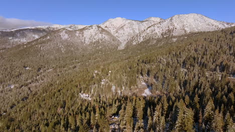 Luftzug-Weg-Von-Bergen-Und-über-Douglasien-Und-Ein-Kleines-Stück-Straße-In-Lake-Tahoe,-Nevada-An-Einem-Wunderschönen-Wintertag-Mit-Blauem-Himmel