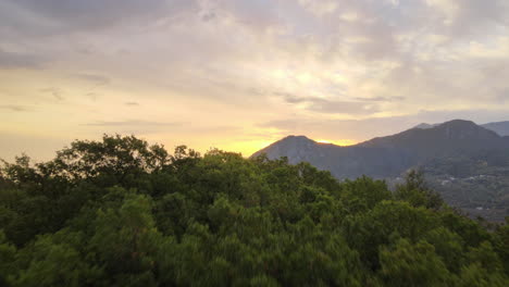 Hermoso-Reenvío-Aéreo-Del-Amanecer-Sobre-Una-Cordillera-Escénica-Con-Vistas-A-Un-Pequeño-Pueblo-En-Las-Estribaciones-De-La-Cordillera-Con-Una-Exuberante-Vegetación-Verde-En-Montenegro